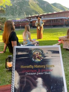 People sitting in the grass with a book in the foreground.