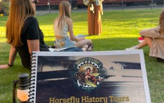 People sitting in the grass with a book in the foreground.