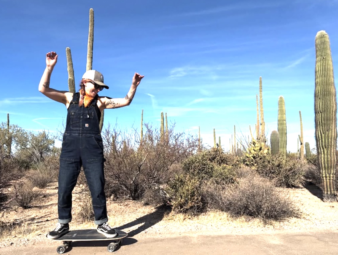 Woman riding skateboard in desert.