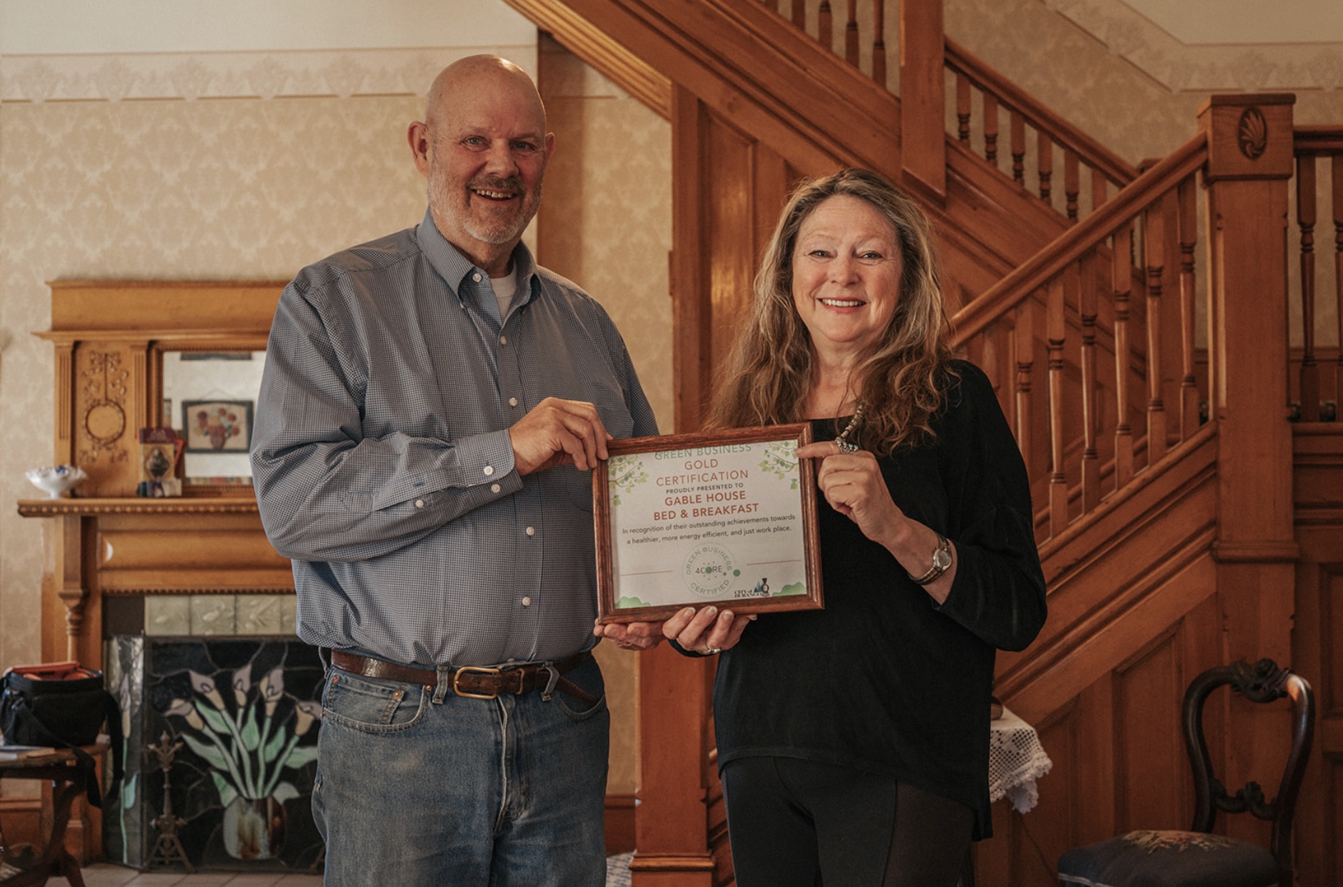 Two people standing in a house holding a plaque.